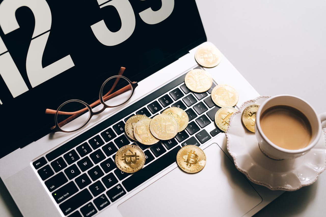 about-02 Laptop keyboard covered with Bitcoin coins and a coffee cup nearby, symbolizing cryptocurrency and work balance.