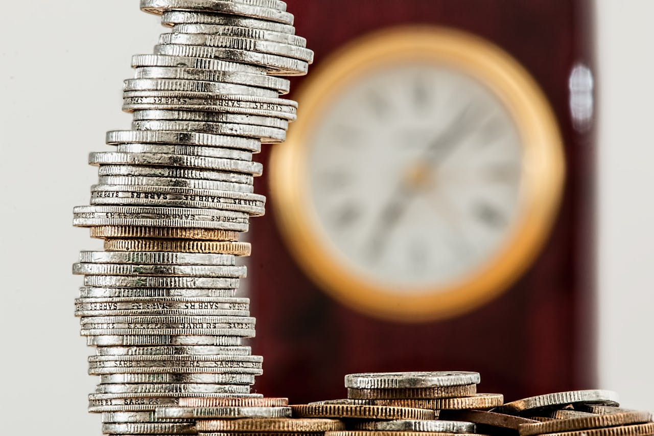 service-01 A close-up image of stacked coins with a blurred clock, symbolizing time and money relationship.
